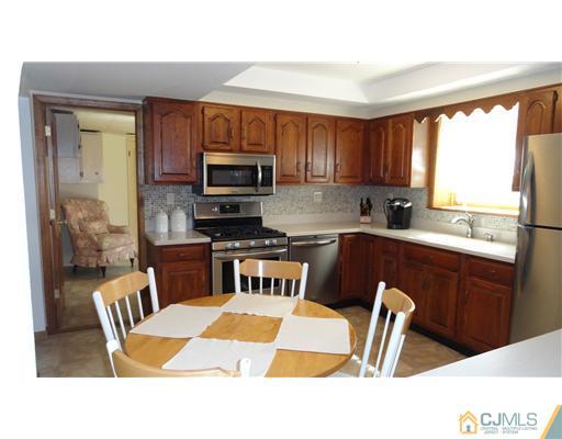 6 Harmon Road Edison, NJ 08837 - Photo 3 of 19 a kitchen with a stove a sink a microwave a dining table and chairs