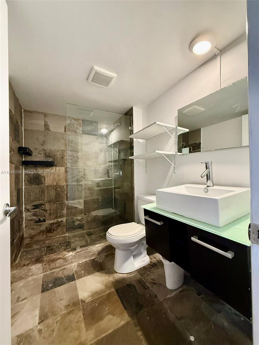 1605 Bay Road, Unit 407 Miami Beach, FL 33139 - Photo 22 of 31 a bathroom with a sink toilet a mirror and shower