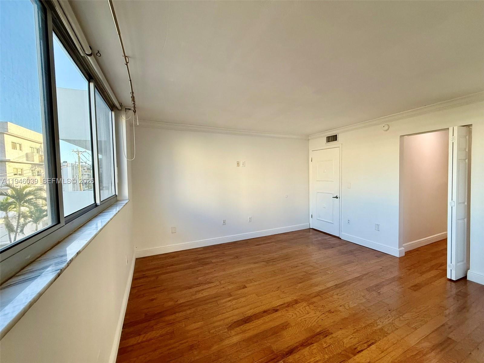 1605 Bay Road, Unit 407 Miami Beach, FL 33139 - Photo 26 of 31 a view of an empty room with wooden floor and a window