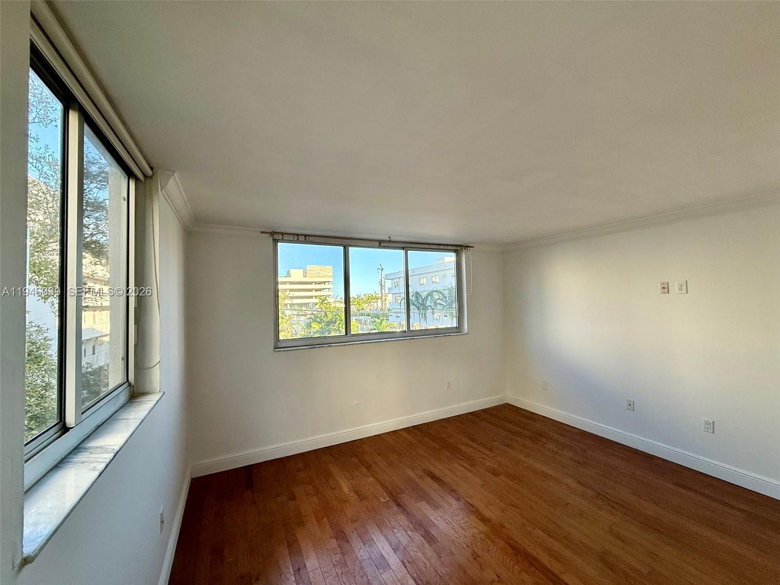 1605 Bay Road, Unit 407 Miami Beach, FL 33139 - Photo 27 of 31 a view of an empty room with wooden floor and a window