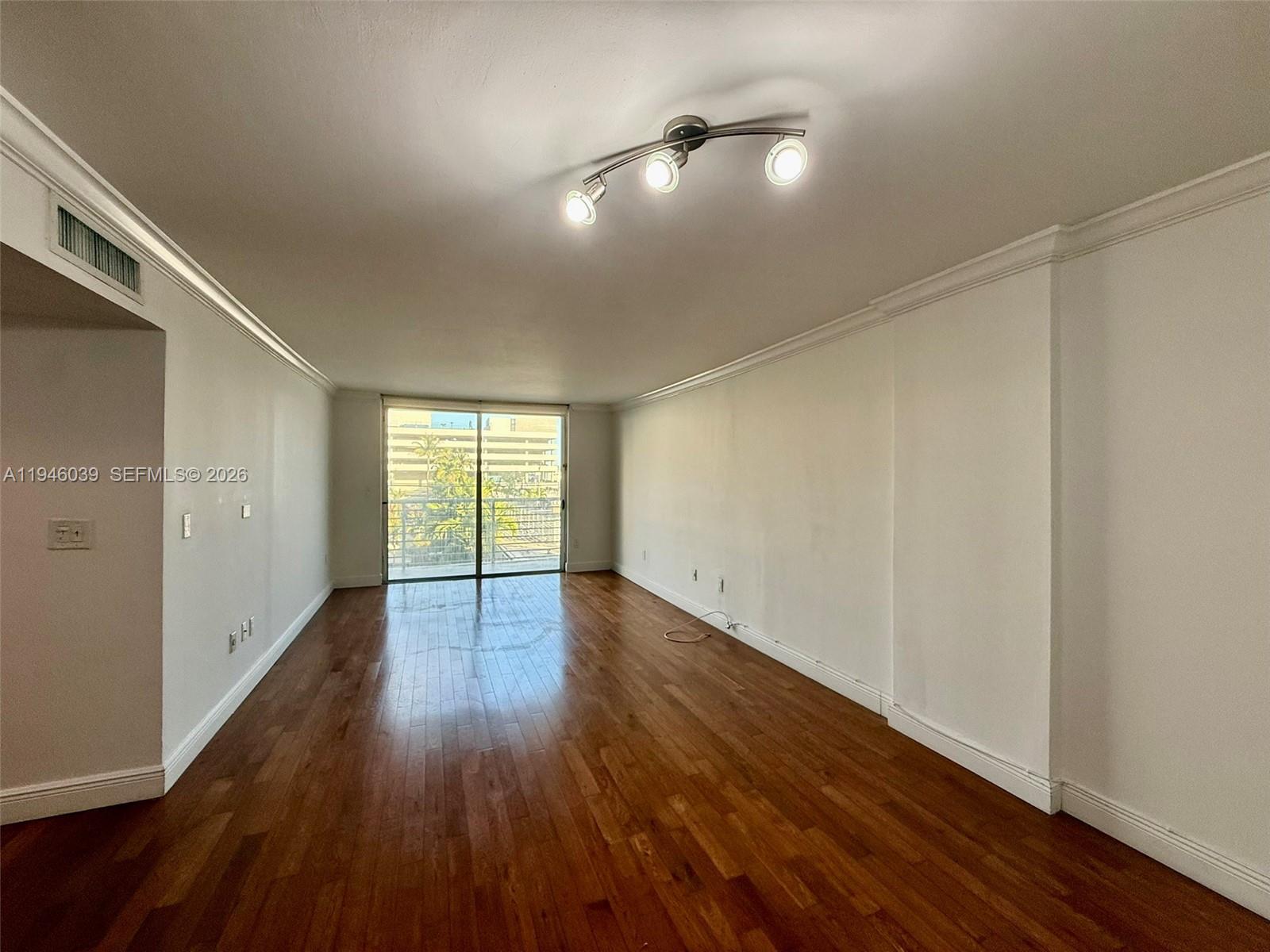 1605 Bay Road, Unit 407 Miami Beach, FL 33139 - Photo 8 of 31 a view of an empty room with wooden floor and a window