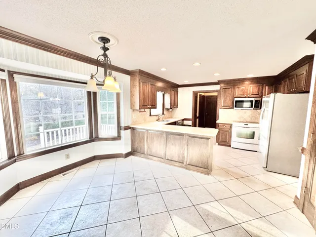 a large white kitchen with granite countertop a stove a sink dishwasher and a refrigerator with cabinets