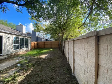 a view of a backyard with large trees and a barn