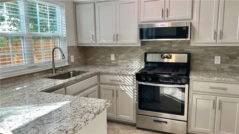 a kitchen with granite countertop a stove sink and cabinets