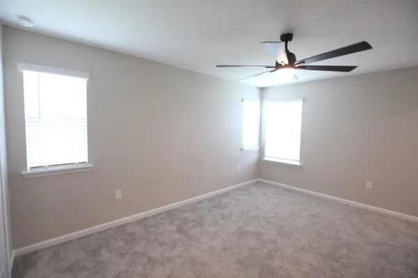 an empty room with windows and fan
