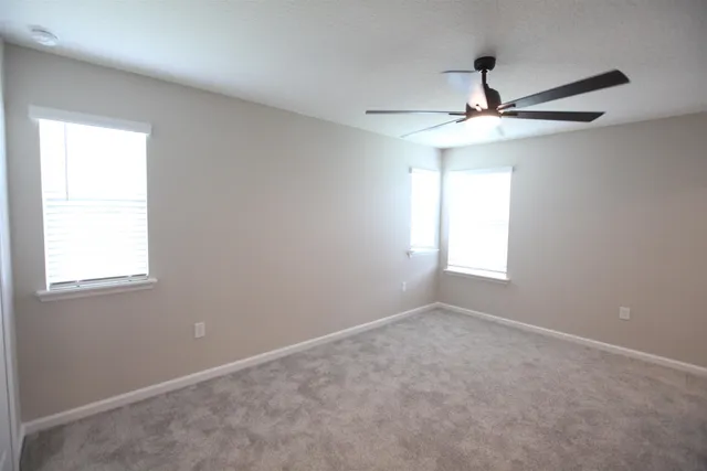 an empty room with windows and fan