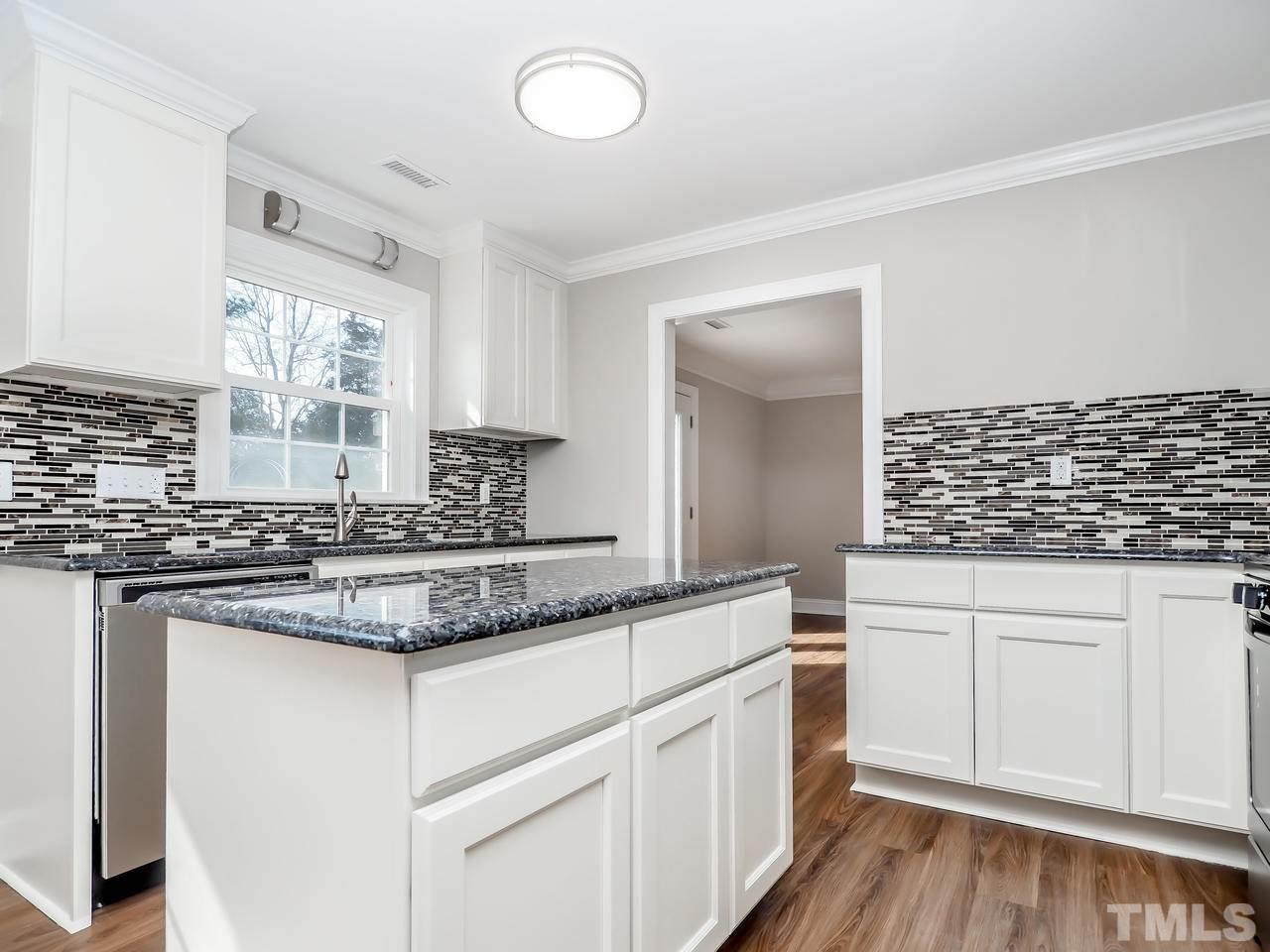 1111 Wyldewood Road Durham, NC 27704 - Photo 7 of 17 a kitchen with stainless steel appliances granite countertop a sink and cabinets with wooden floor