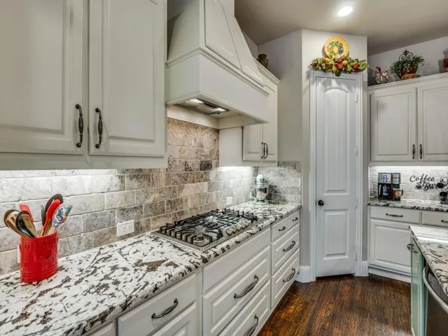a kitchen with stainless steel appliances granite countertop a table chairs stove and refrigerator