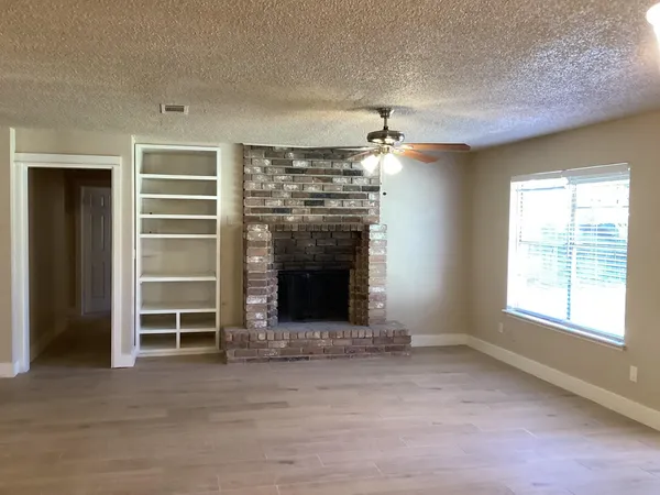 a view of an empty room with a fireplace and a window
