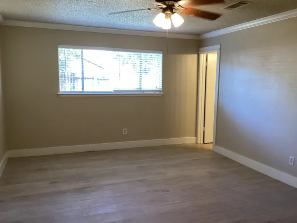 an empty room with windows and chandelier fan