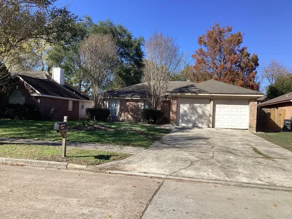 a view of a house with a yard and large tree