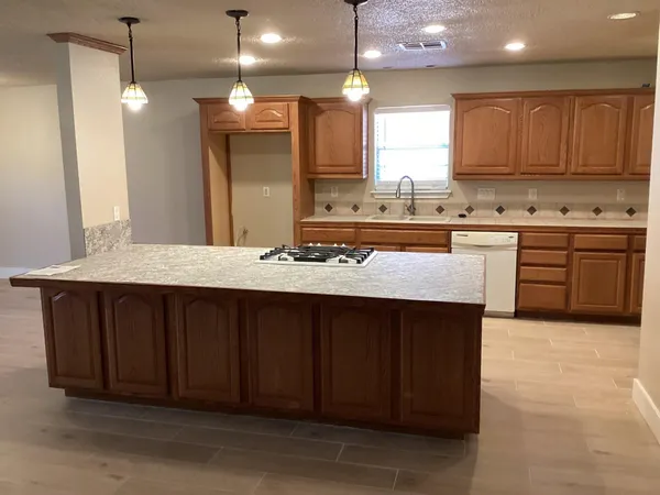 a kitchen with kitchen island granite countertop wooden cabinets and a sink