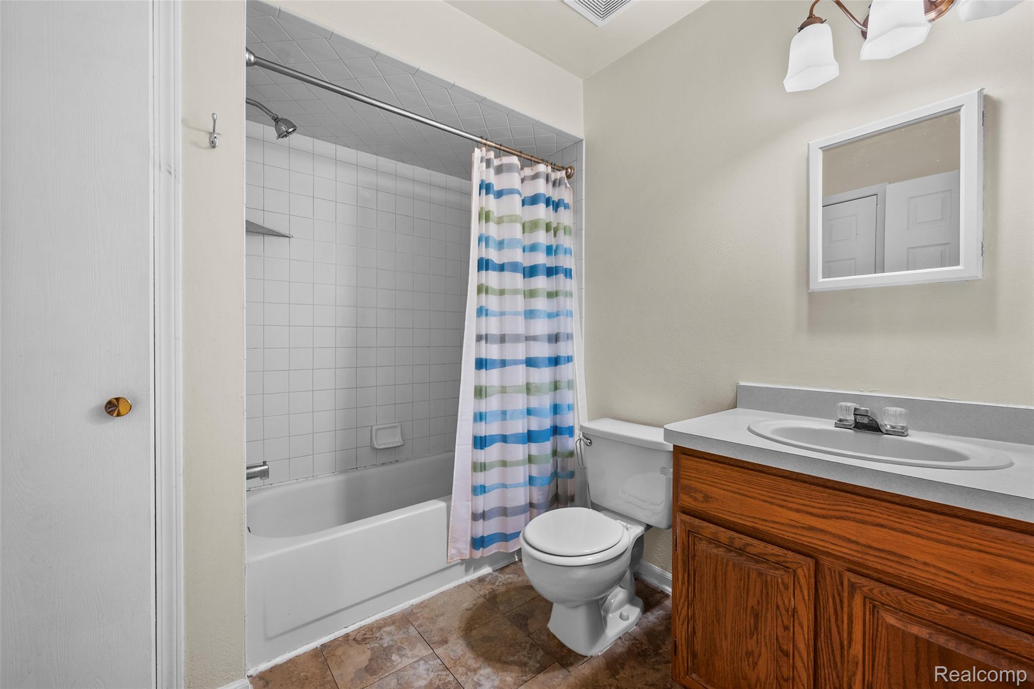 200 Fraser Street Rochester, MI 48307 - Photo 13 of 29 Bathroom featuring a white bathtub with tile surround, a toilet, and a vanity with a built-in sink