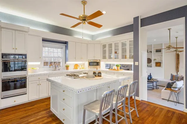 a kitchen with stainless steel appliances granite countertop a stove a sink dishwasher and a dining table with wooden floor