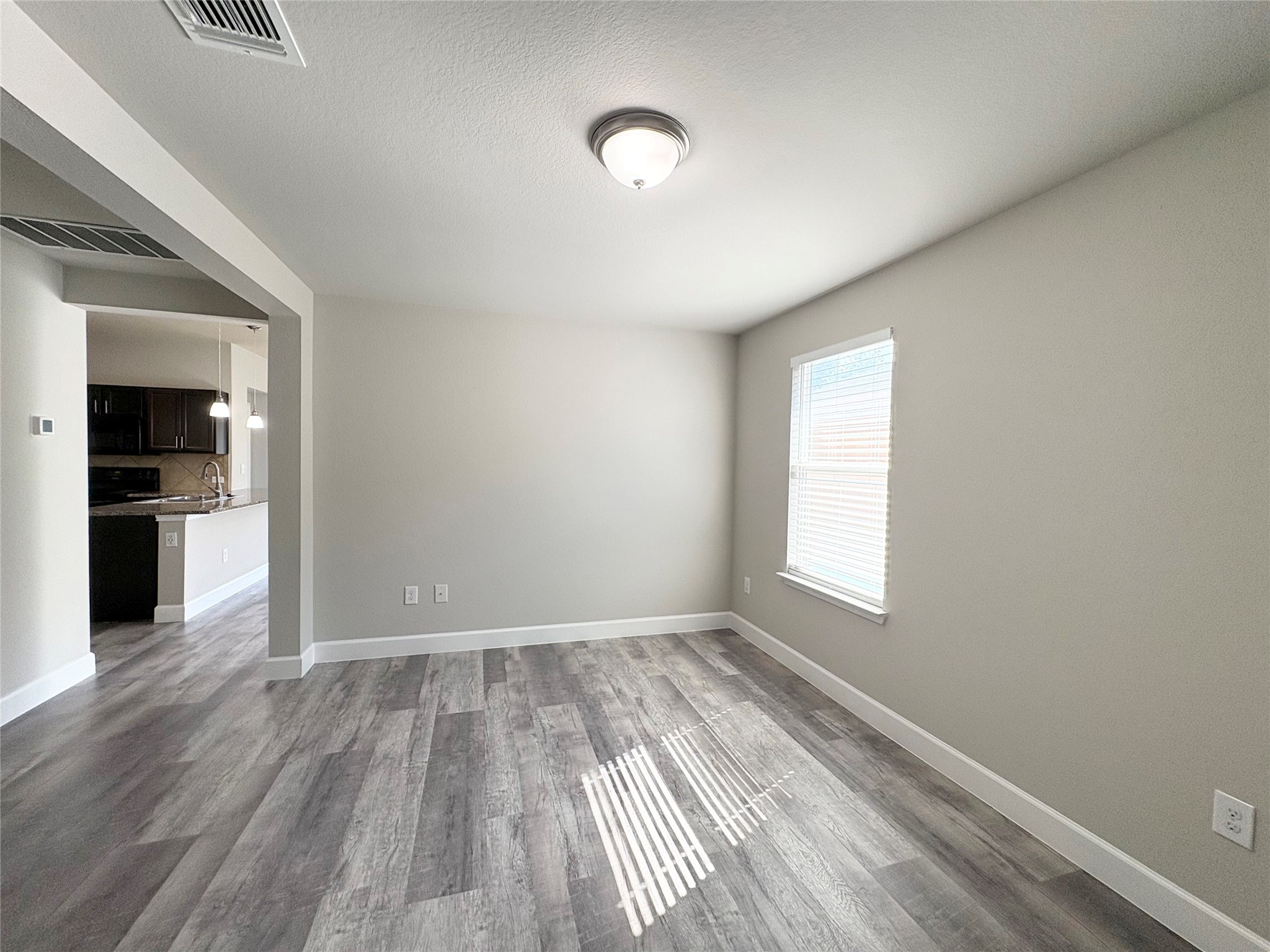 11708 Cambrian Road Manor, TX 78653 - Photo 6 of 31 Natural light streams into this versatile living area, showcasing its attractive flooring and open flow to the kitchen.
