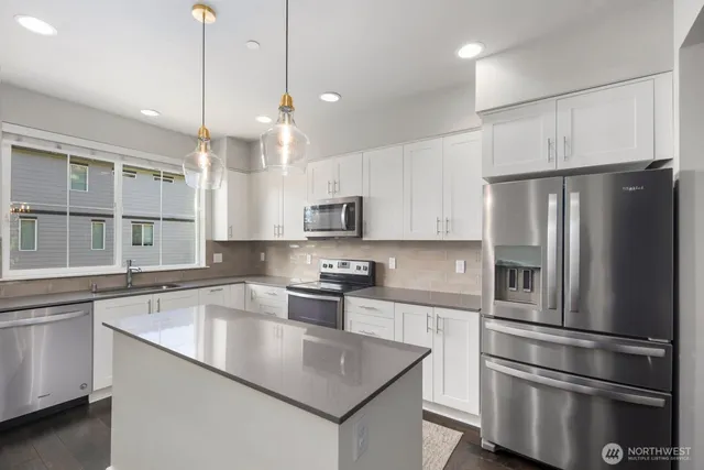 a kitchen with stainless steel appliances granite countertop a sink a stove and a white cabinets