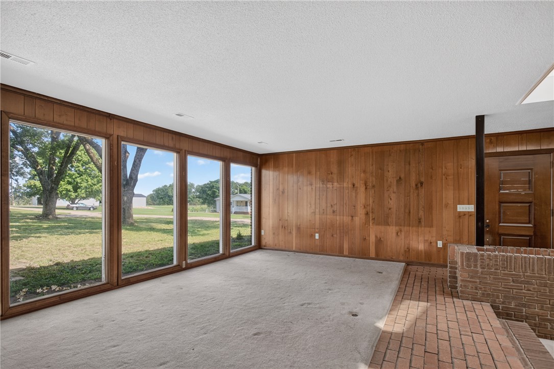 1412 Simpson Road Pendleton, SC 29670 - Photo 3 of 48 Floor-to-ceiling windows showcase verdant views, complementing the wood paneling and brickwork within this spacious living area.