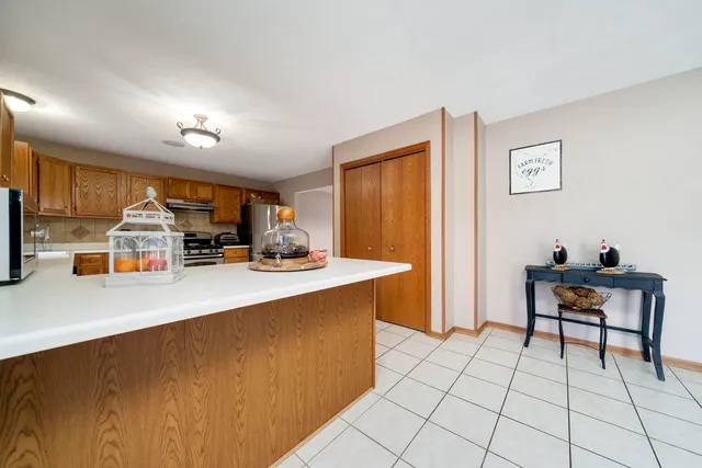 a view of a kitchen with kitchen island stainless steel appliances refrigerator sink dining table and chairs