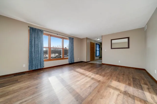 a view of an empty room with a window and wooden floor
