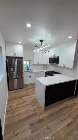 a large kitchen with a stove a refrigerator a sink dishwasher with wooden cabinets and floors