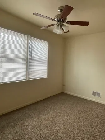 an empty room with a ceiling fan and a window