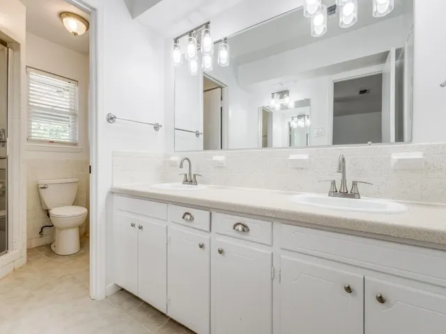 a bathroom with a granite countertop sink a toilet and a mirror