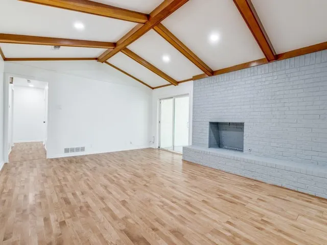 a view of empty room with wooden floor and fireplace