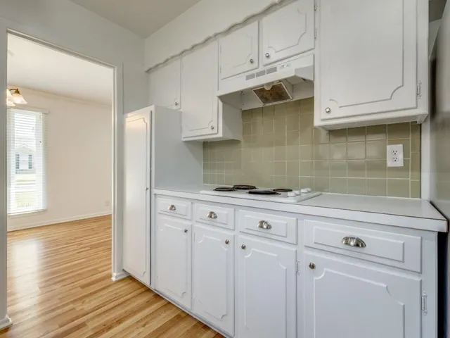 a kitchen with stainless steel appliances granite countertop a refrigerator and white cabinets with wooden floor