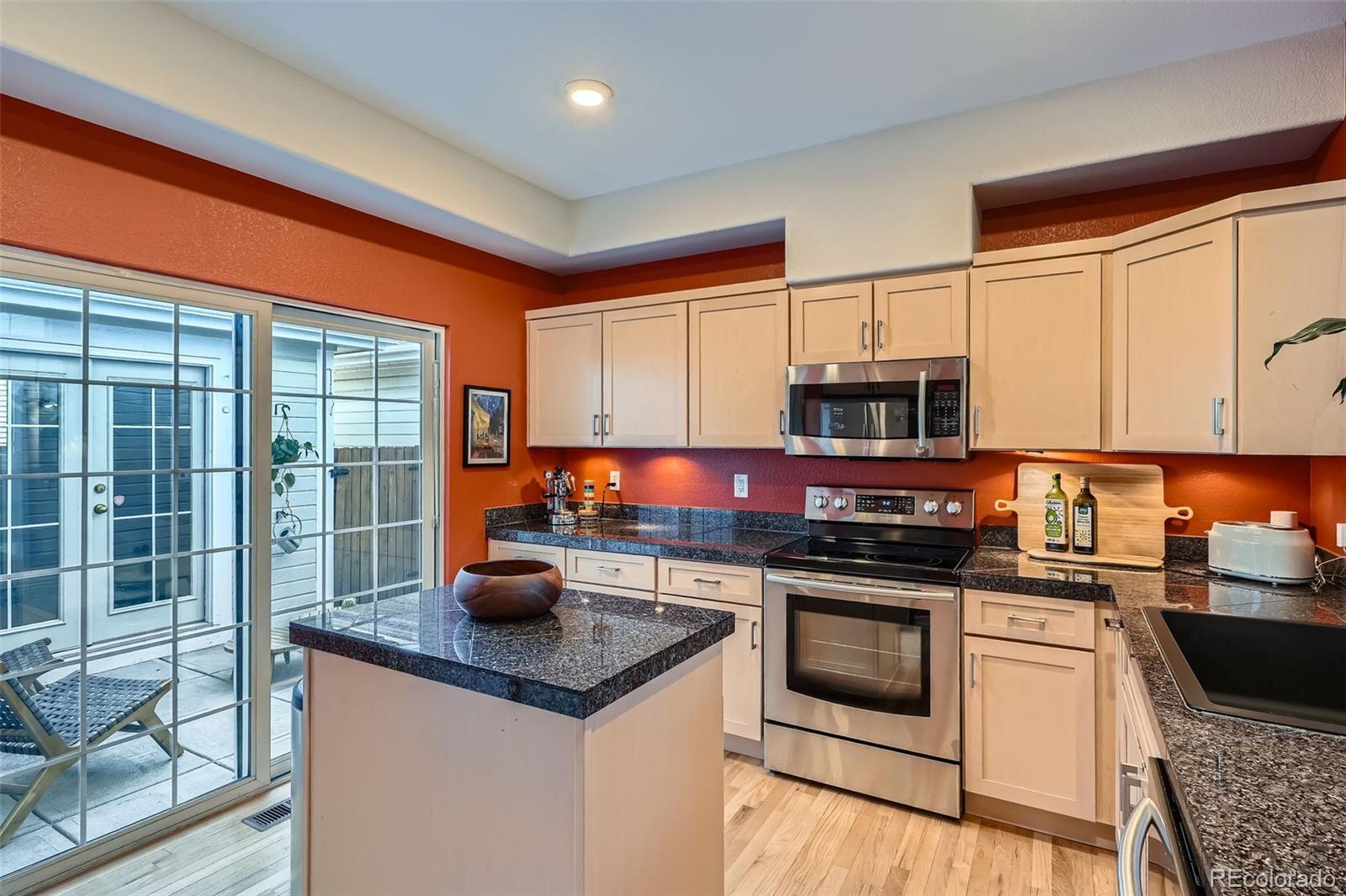 8300 Fairmount Drive, Unit AA102 Denver, CO 80247 - Photo 7 of 27 a kitchen with stainless steel appliances kitchen island granite countertop a stove top oven