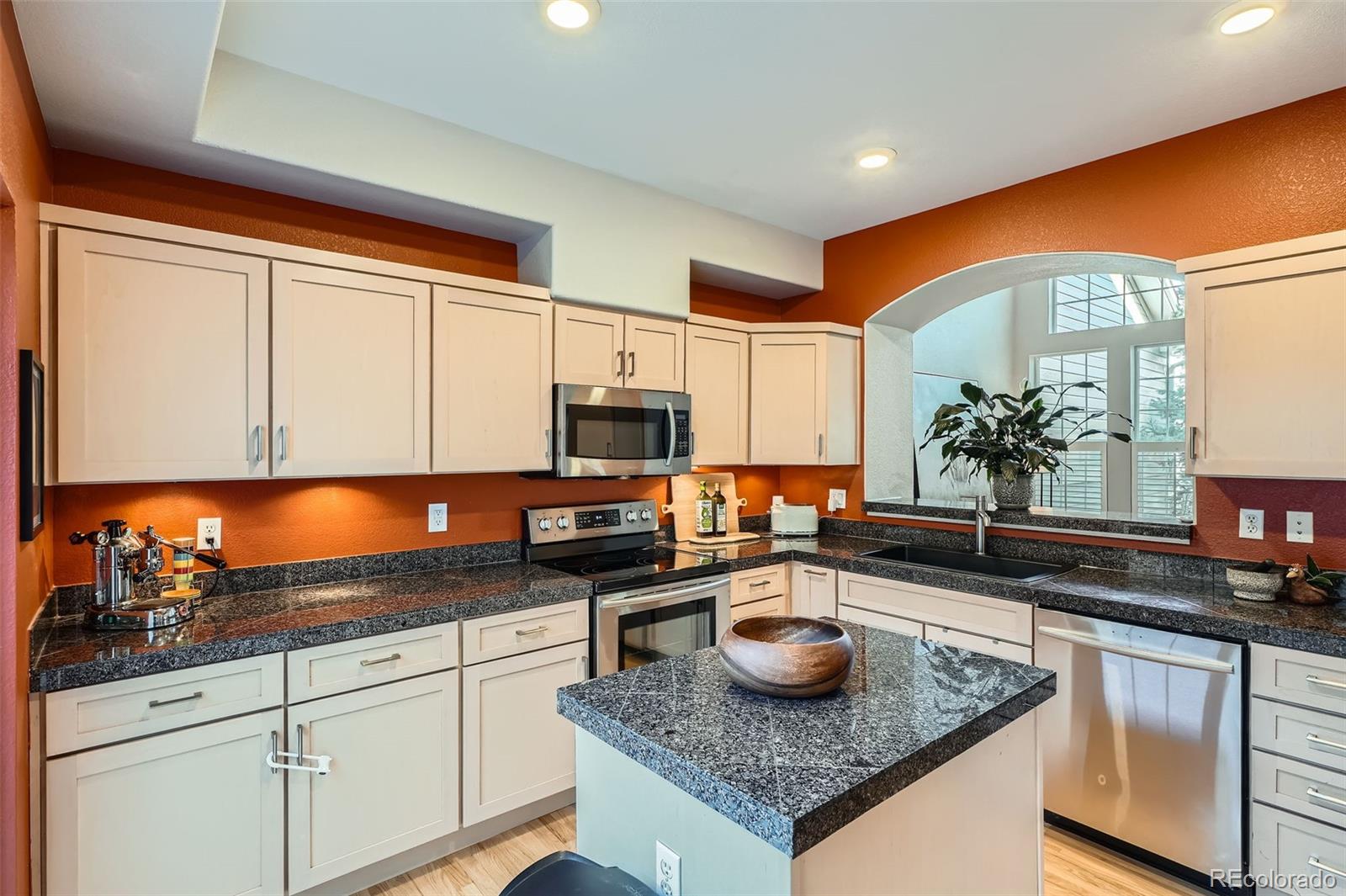 8300 Fairmount Drive, Unit AA102 Denver, CO 80247 - Photo 8 of 27 a kitchen with stainless steel appliances granite countertop a sink a stove and a microwave