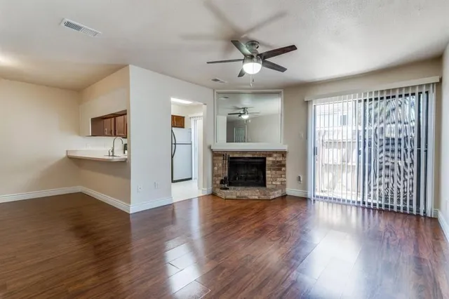 a view of a livingroom with wooden floor a ceiling fan and windows