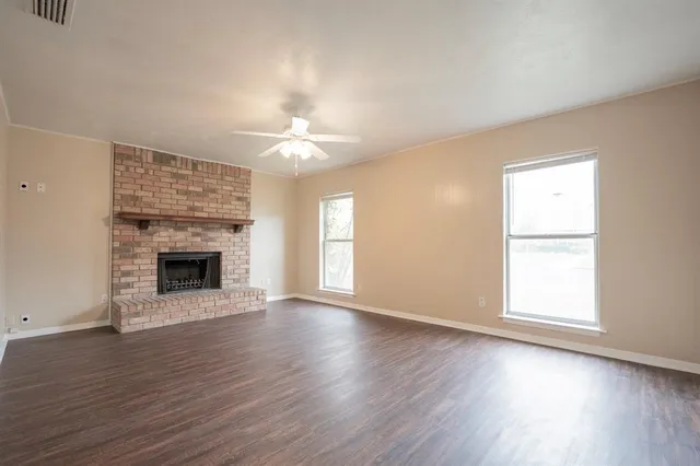 an empty room with wooden floor a fireplace and windows