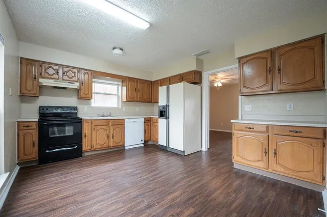 a kitchen with granite countertop a refrigerator and a stove top oven
