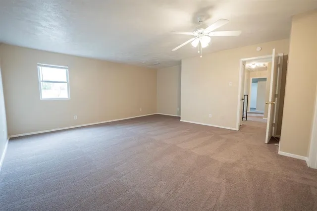 an empty room with a chandelier fan and windows