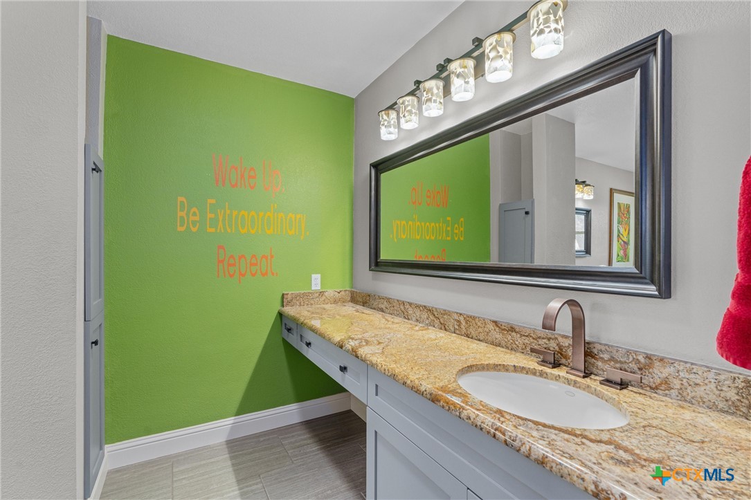 404 Skyline Road Georgetown, TX 78628 - Photo 19 of 40 a bathroom with a granite countertop sink and a mirror