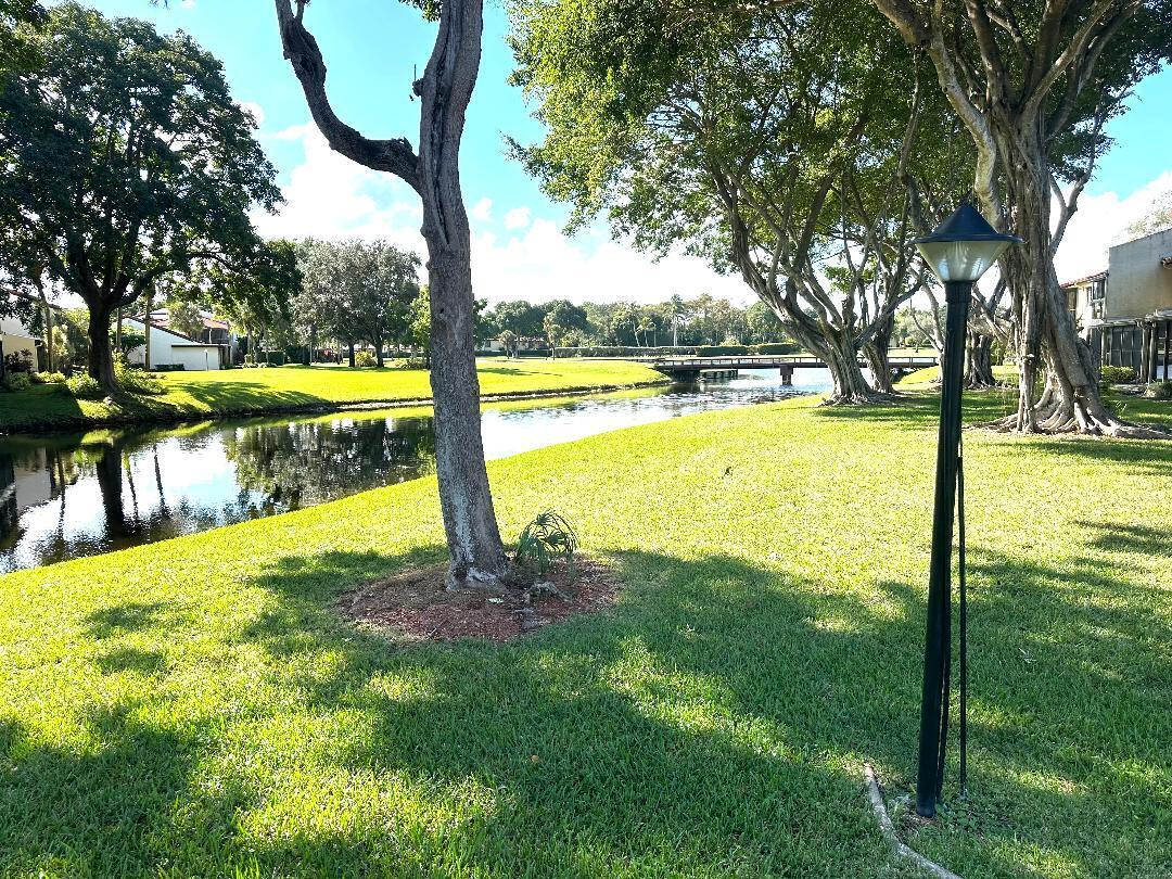 8305 Casa Del Lago, Unit E Boca Raton, FL 33433 - Photo 14 of 16 a view of a swimming pool with a yard and large trees