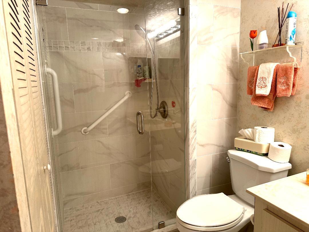 8305 Casa Del Lago, Unit E Boca Raton, FL 33433 - Photo 10 of 16 a white toilet sitting next to a bathroom sink and a shower