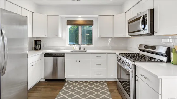 a kitchen with white cabinets stainless steel appliances and sink