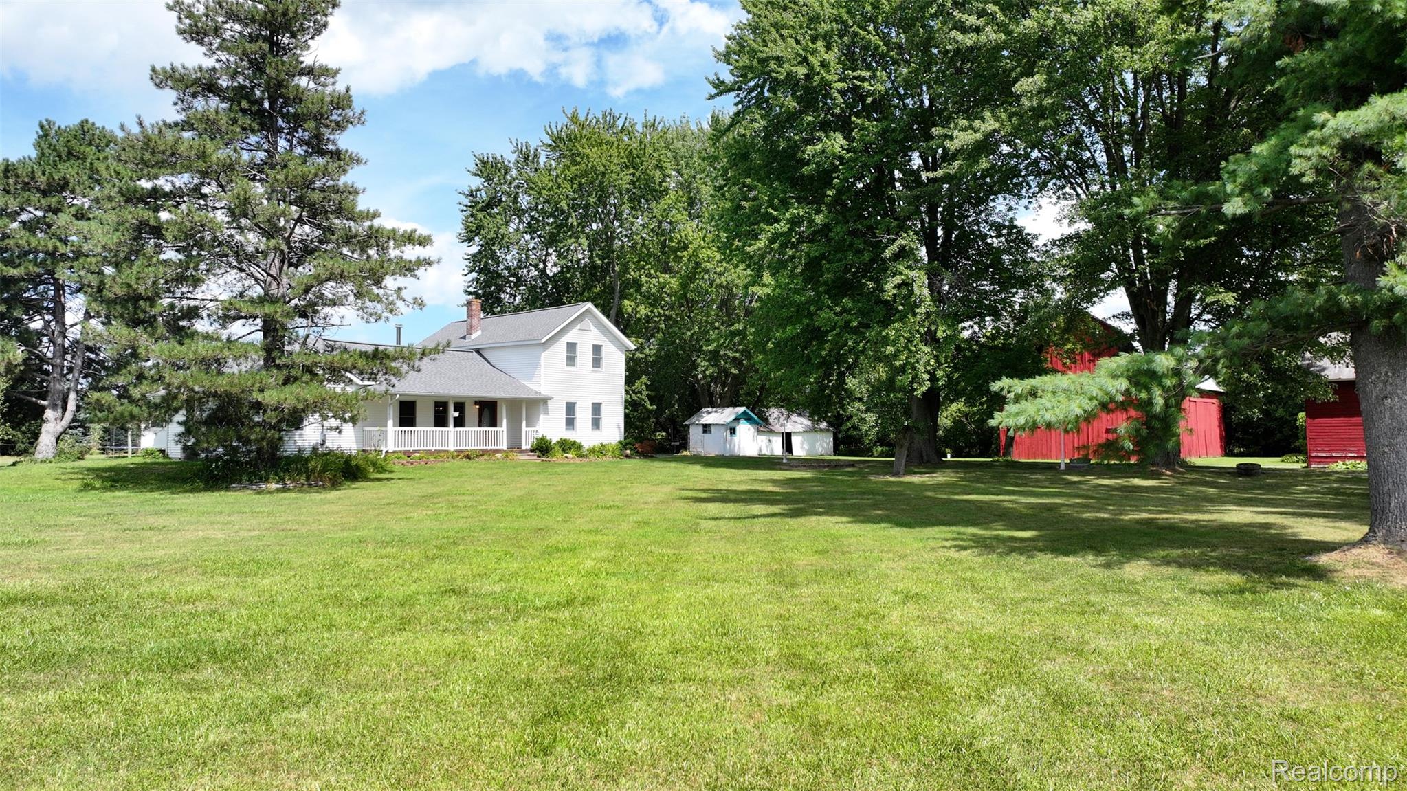 12930 Wilkinson Road Freeland, MI 48623 - Photo 5 of 76 Expansive grassy lawn with mature trees and a white two-story residence featuring a covered porch