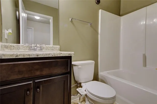 a bathroom with a granite countertop toilet sink and mirror