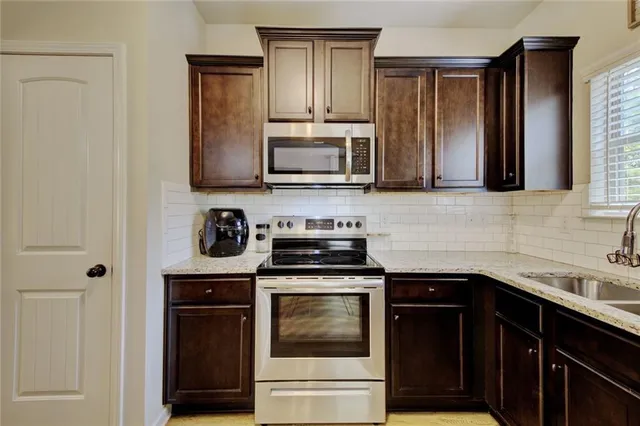 a kitchen with granite countertop a stove sink and microwave