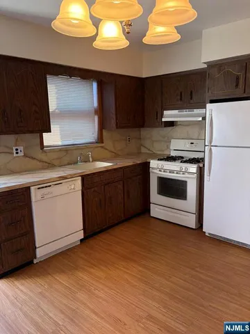 a kitchen with stainless steel appliances a sink cabinets and wooden floor