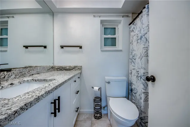 a bathroom with a granite countertop toilet sink and mirror