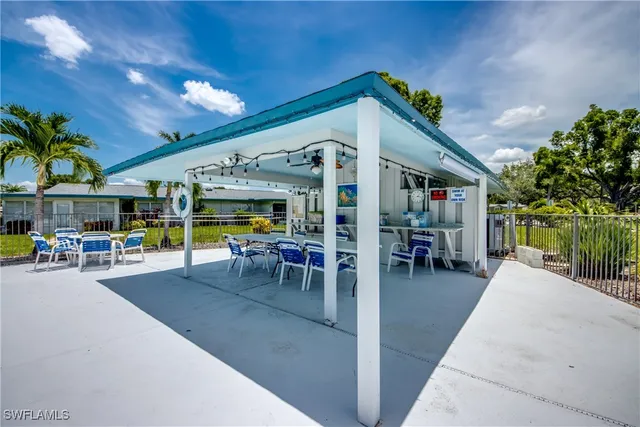 a view of a patio with dining table and chairs under an umbrella with palm trees