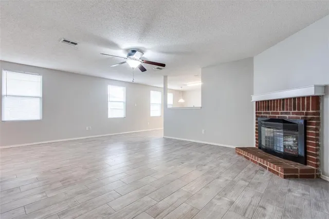 an empty room with windows and fireplace