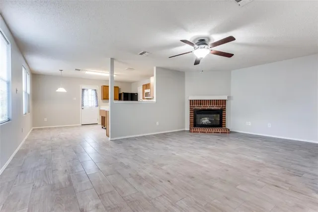 a view of an empty room with a fireplace and a ceiling fan