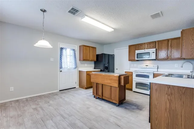 a large kitchen with stainless steel appliances a sink a stove a refrigerator cabinets and wooden floor