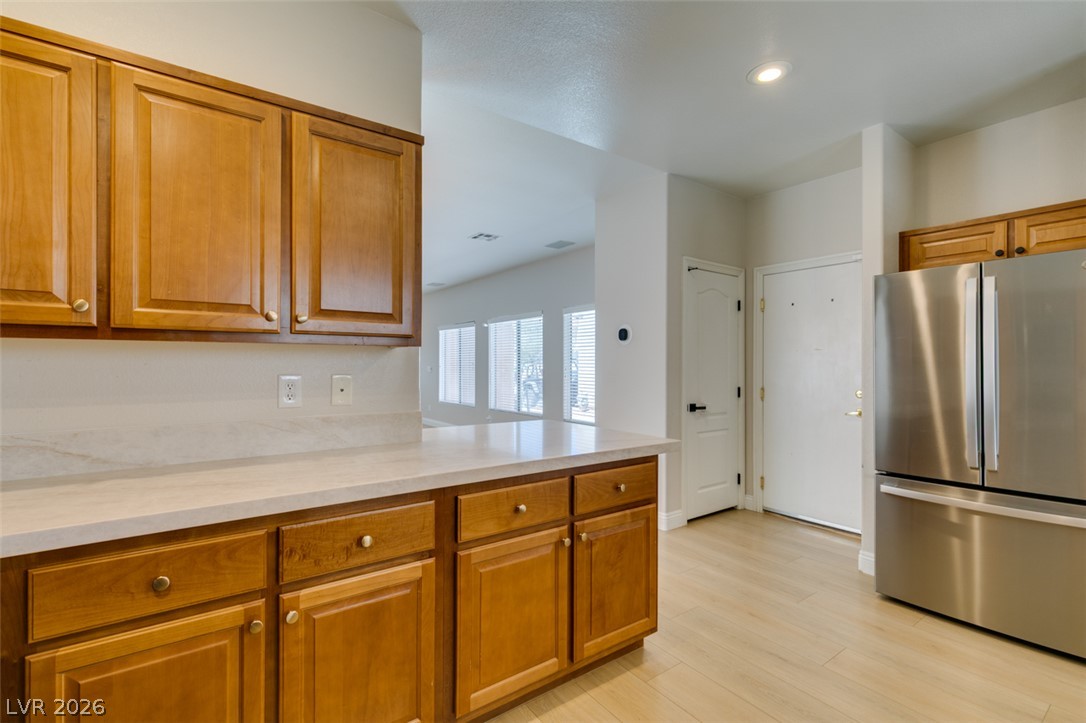 8909 Houston Ridge Avenue Las Vegas, NV 89178 - Photo 22 of 45 A clean kitchen area showcases warm cabinetry, light countertops, and durable flooring, with a glimpse of an adjacent room.