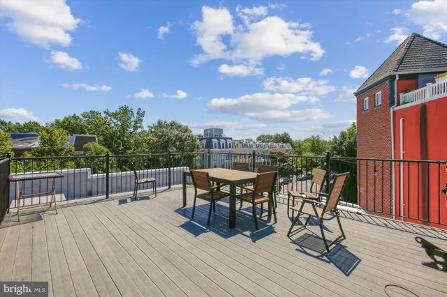 a view of a roof deck with table and chairs a barbeque with wooden floor and fence