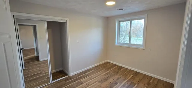 a view of a hallway with wooden floor and closet